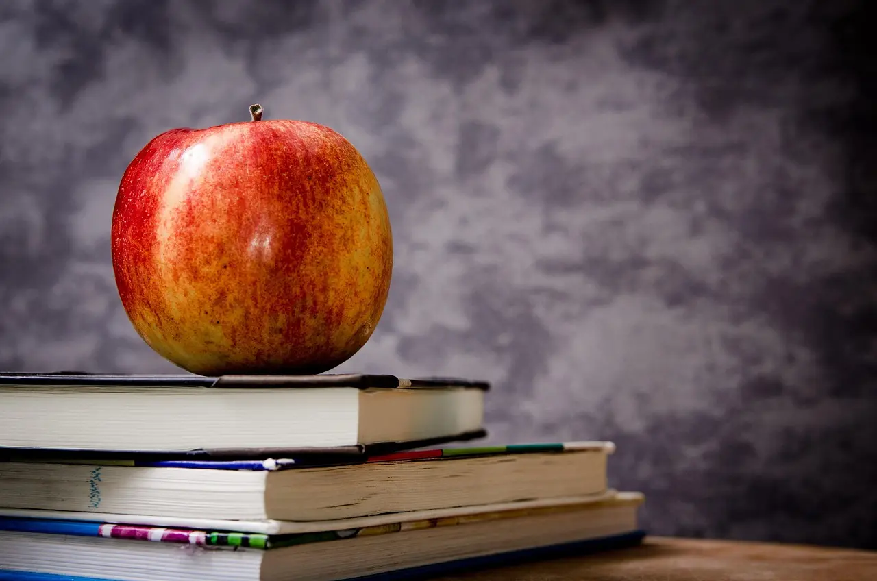 Master per classi di concorso e punteggio GPS Mela rossa su una pila di libri, simbolo dell'insegnamento: master per classi di concorso e punteggio GPS